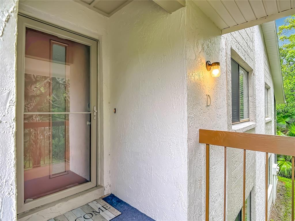 A white stucco exterior wall features a front door, a light fixture, and unit letter D — 12308 EAGLESWOOD DRIVE UNIT D, HUDSON, FL