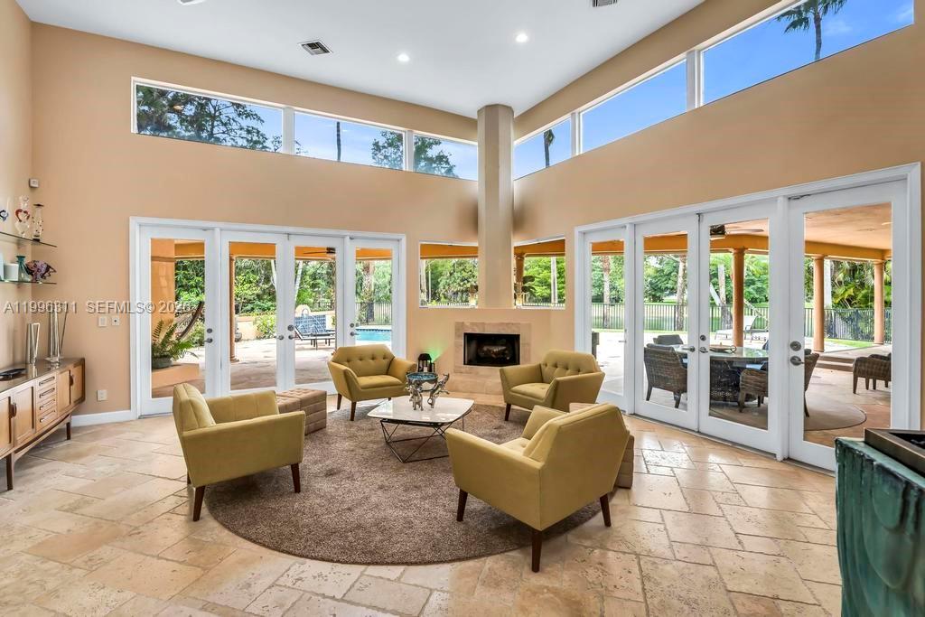 A living room with high ceilings, a fireplace, and glass doors leading to a patio — 5328 E Leitner Dr, Coral Springs FL 33067, CORAL SPRINGS, FL