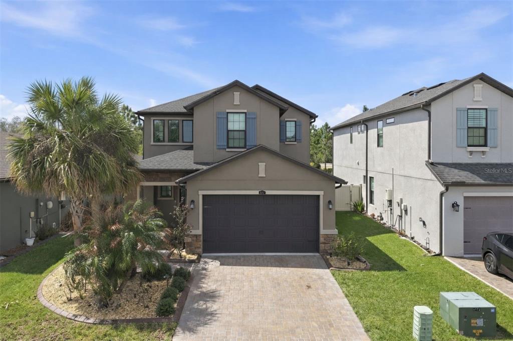 A two-story suburban house with a gray exterior, a two-car garage, and a paved driveway — 4547 SAN MARTINO DRIVE, WESLEY CHAPEL, FL