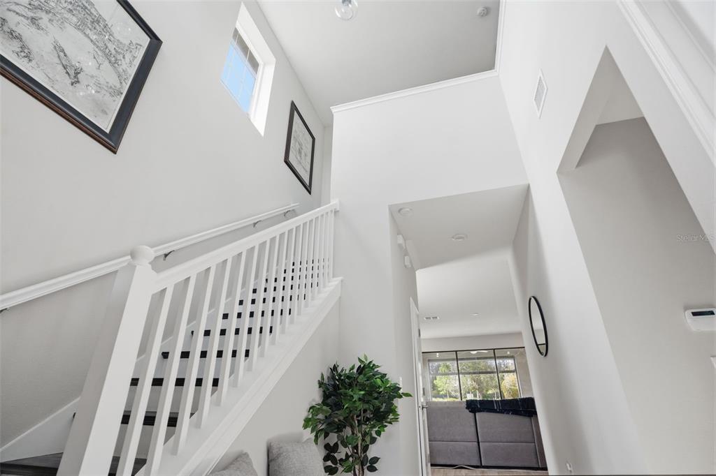 A bright entryway features a white staircase with dark treads and a high ceiling — 4547 SAN MARTINO DRIVE, WESLEY CHAPEL, FL