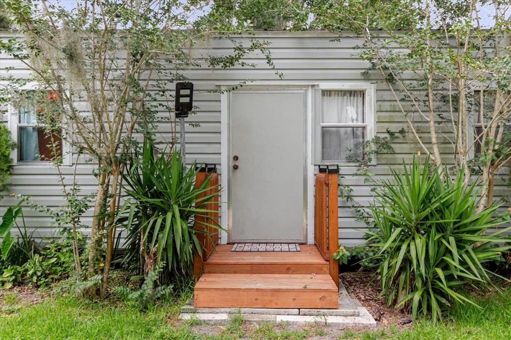 A light gray mobile home exterior features a central door with wooden steps and railings — 9916 E GULF TO LAKE HIGHWAY, INVERNESS, FL