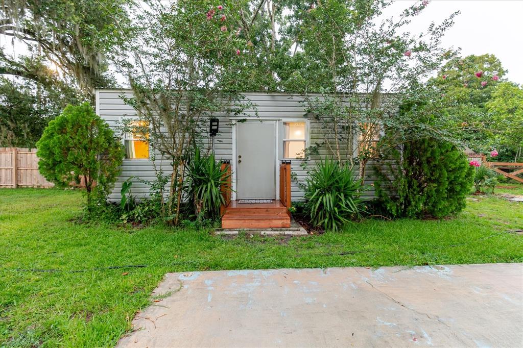A small, light-gray siding exterior building with a wooden porch and surrounding trees — 9916 E GULF TO LAKE HIGHWAY, INVERNESS, FL