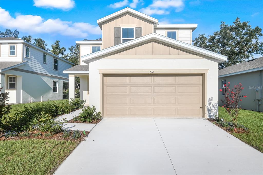 A two-story house with a beige garage door and white stucco exterior under a blue sky — 734 LAKE DELL AVENUE, DUNDEE, FL