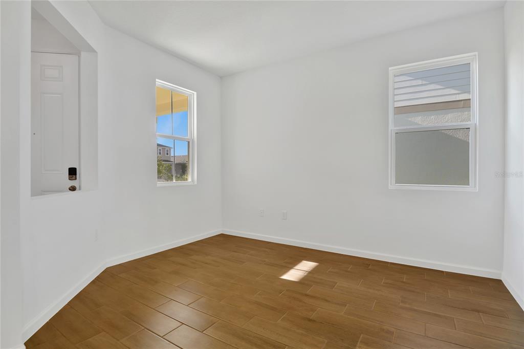 An empty room with white walls, wood-look tile flooring, and two windows — 734 LAKE DELL AVENUE, DUNDEE, FL