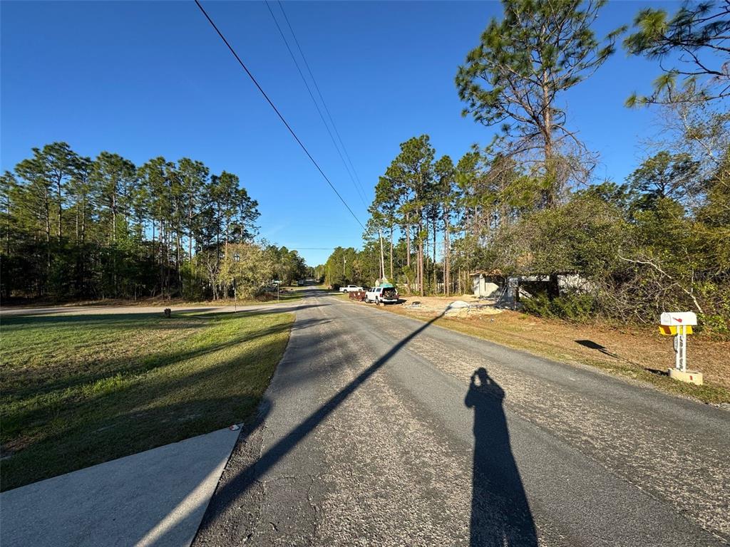 A paved road stretches into a wooded area with a house under construction on the right — 7890 N POCONO DRIVE, CITRUS SPRINGS, FL