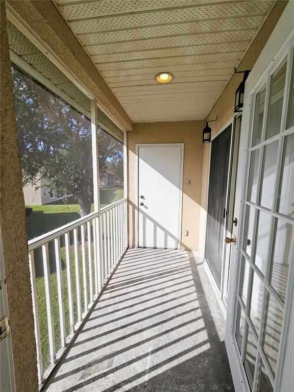 A screened-in balcony features a concrete floor, white railings, and a white exterior door — 2850 OSPREY COVE PLACE UNIT 201, KISSIMMEE, FL