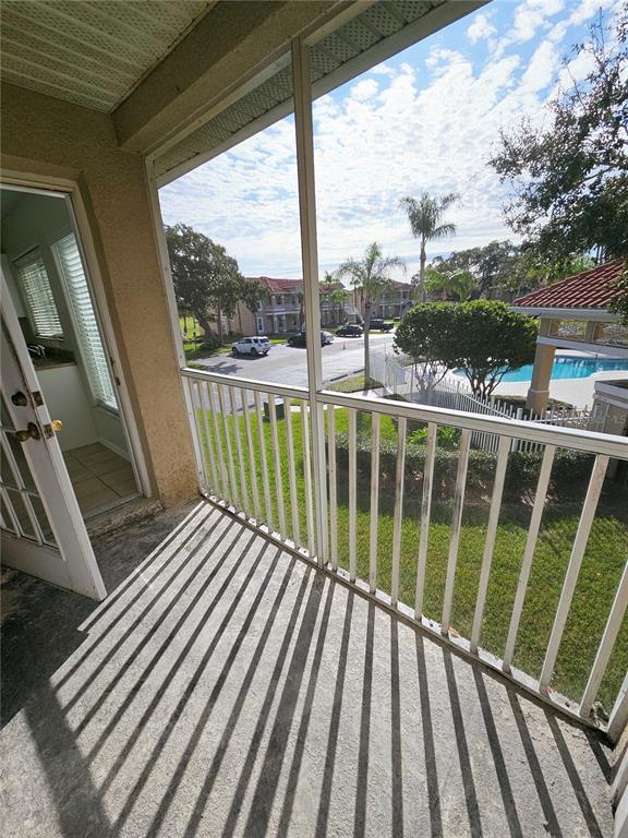 A screened-in balcony overlooks a swimming pool and parking area with palm trees — 2850 OSPREY COVE PLACE UNIT 201, KISSIMMEE, FL