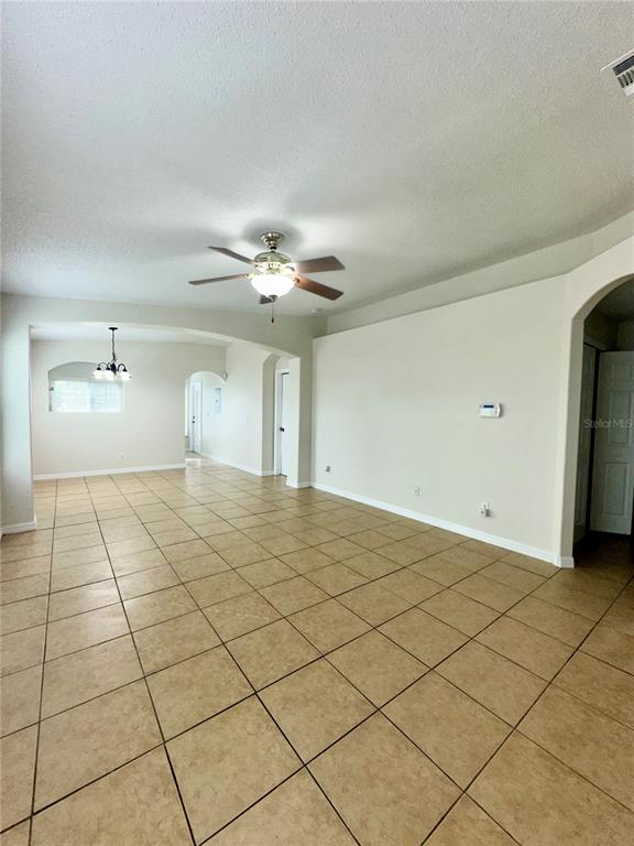 An open-concept living area features light-colored tile flooring, a ceiling fan, and arched doorways — 2850 OSPREY COVE PLACE UNIT 201, KISSIMMEE, FL