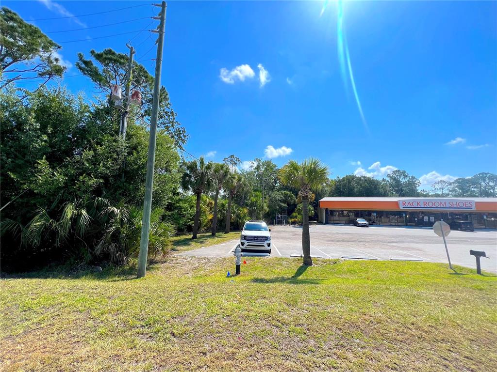 A parking lot sits in front of a Rack Room Shoes store under a sunny sky — W IRLO BRONSON MEMORIAL HIGHWAY, KISSIMMEE, FL
