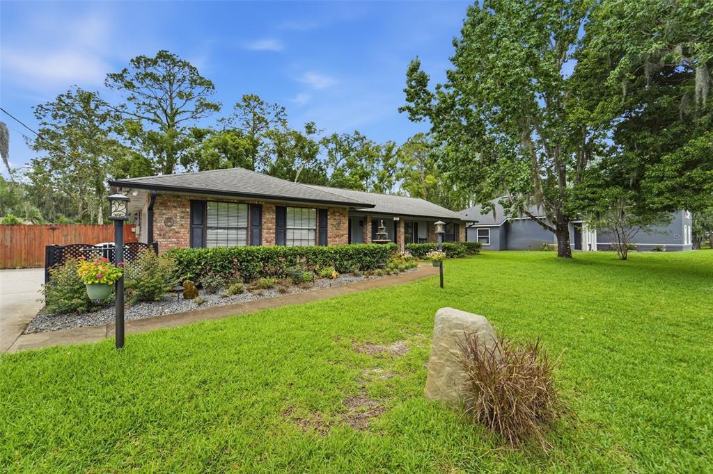 A single-story brick house with a dark shingled roof, shutters, and a landscaped front lawn — 386 LAKE CHARLES ROAD, DELAND, FL