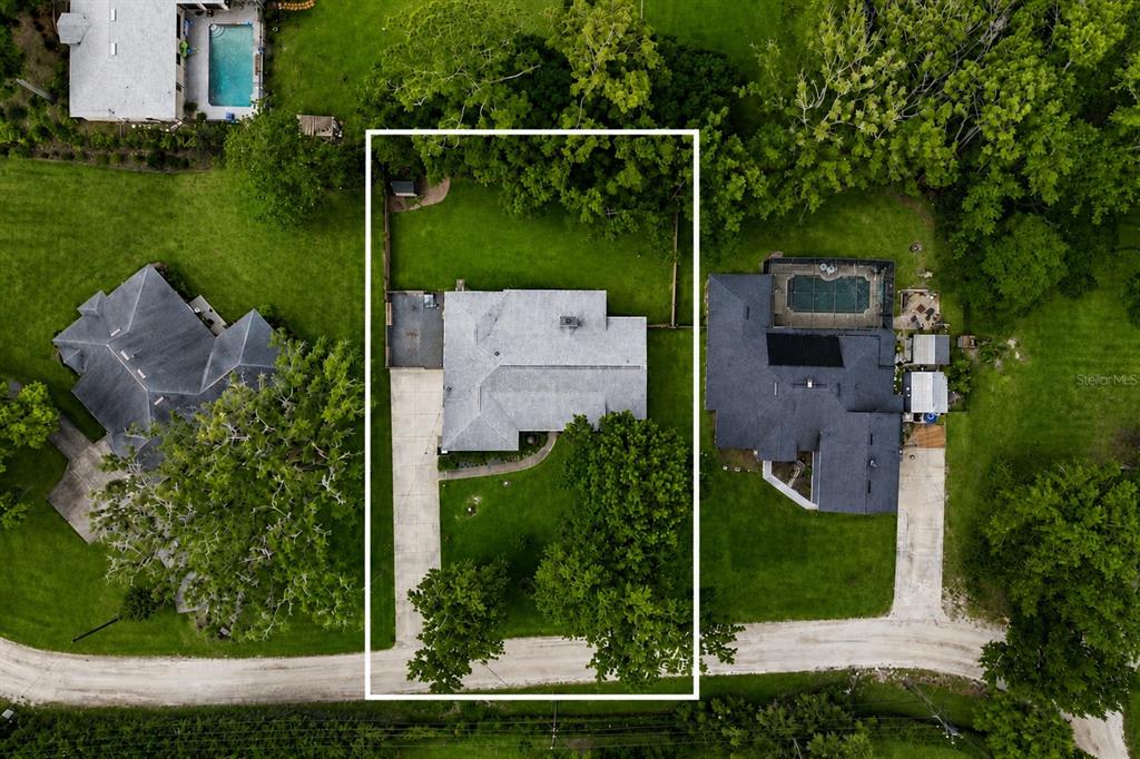 An aerial view shows a single-story house with a driveway and yard within a neighborhood — 386 LAKE CHARLES ROAD, DELAND, FL