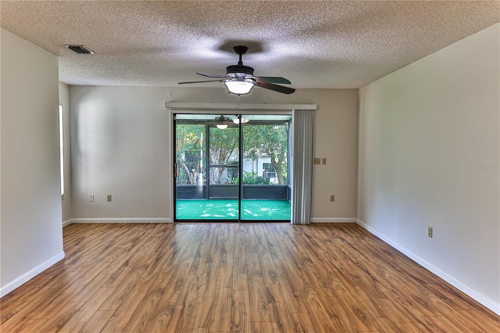 A living room features wood-look flooring, a ceiling fan, and sliding glass doors to a patio — 3333 S LIVERPOOL POINT, INVERNESS, FL