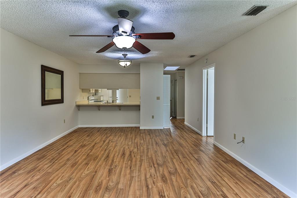 An empty room with wood-look flooring, a ceiling fan, and an open kitchen pass-through window — 3333 S LIVERPOOL POINT, INVERNESS, FL