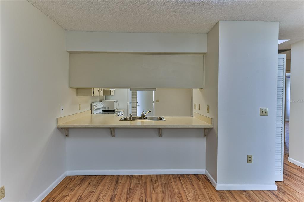 A kitchen pass-through window with a laminate countertop overlooks a sink and stove — 3333 S LIVERPOOL POINT, INVERNESS, FL