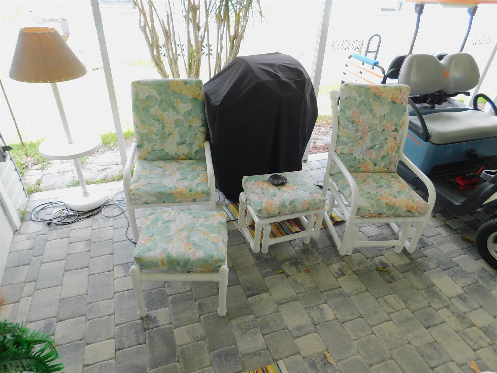A patio area features two floral-patterned chairs, two matching ottomans, a lamp, and a grill — 485 Hemingway Terrace # 04, Fort Pierce FL 34982, FORT PIERCE, FL
