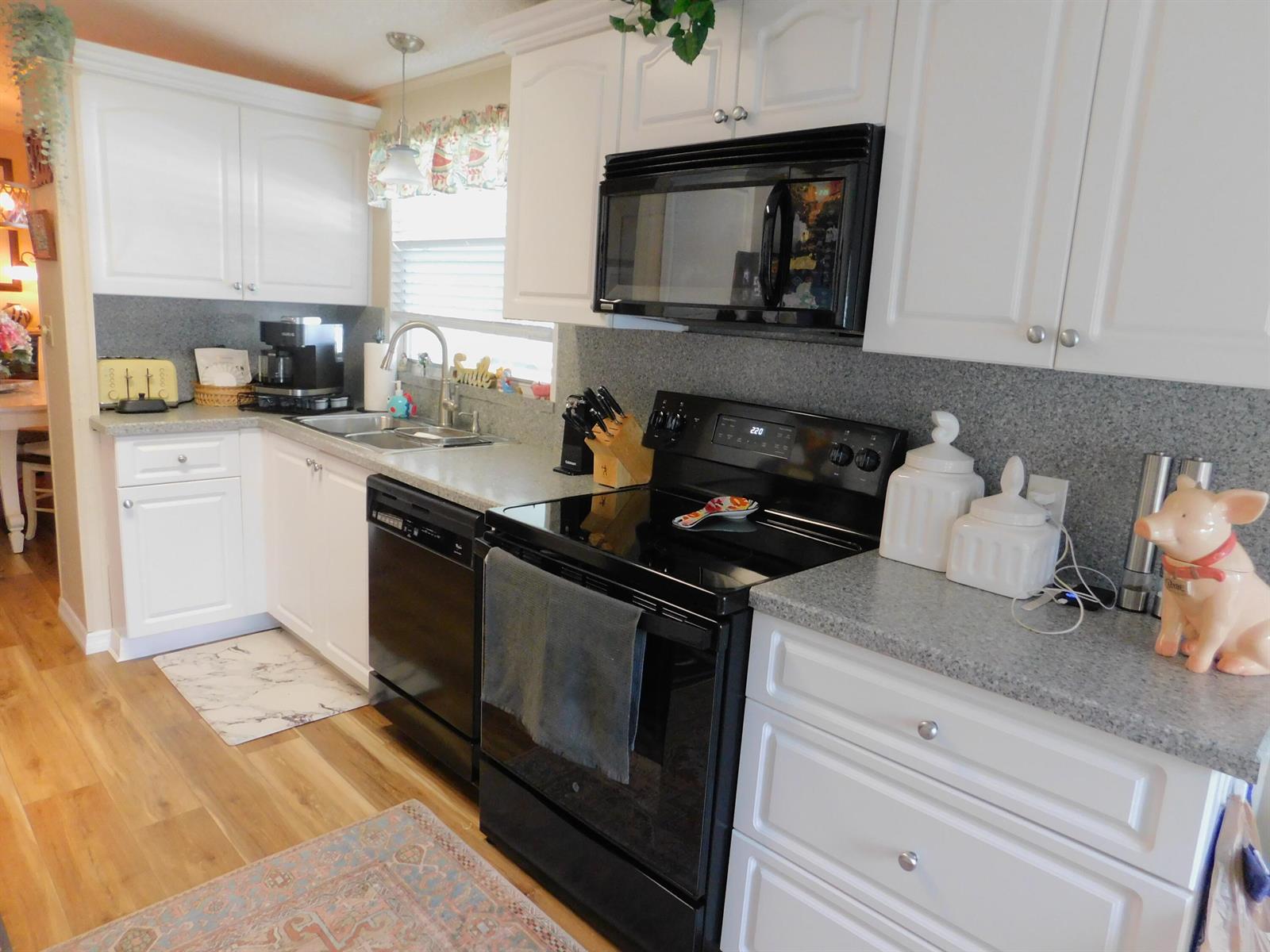 A kitchen features white cabinets, gray countertops, black appliances, and light wood-look flooring — 485 Hemingway Terrace # 04, Fort Pierce FL 34982, FORT PIERCE, FL