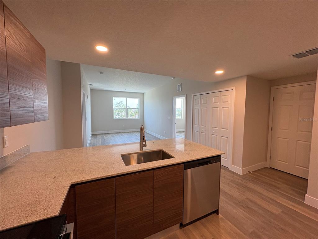 A kitchen with wood-tone cabinets and granite countertops overlooks an open living area — 4424 S TEXAS AVENUE UNIT 1-306, ORLANDO, FL
