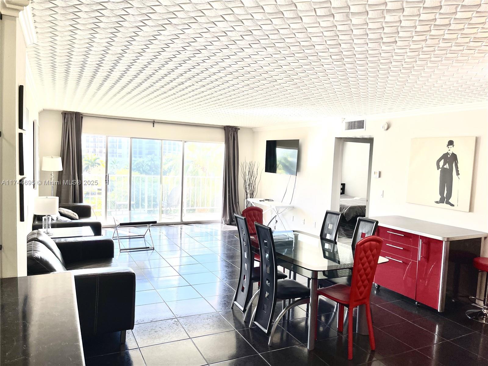 A living and dining area features black tile floors, a textured ceiling, and red accents — 200 178th Dr # 609, Sunny Isles Beach FL 33160, SUNNY ISLES BEACH, FL