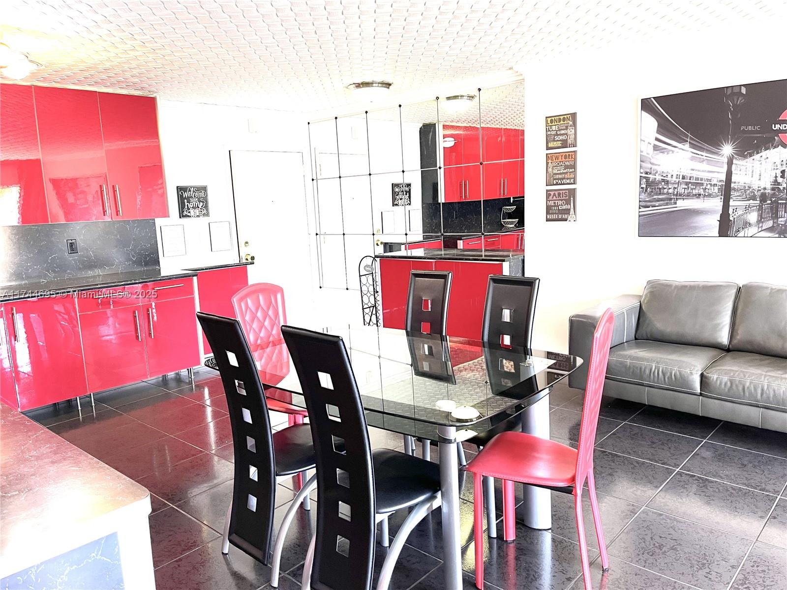 A dining area features a glass table, black chairs, red cabinets, and dark tiled floors — 200 178th Dr # 609, Sunny Isles Beach FL 33160, SUNNY ISLES BEACH, FL