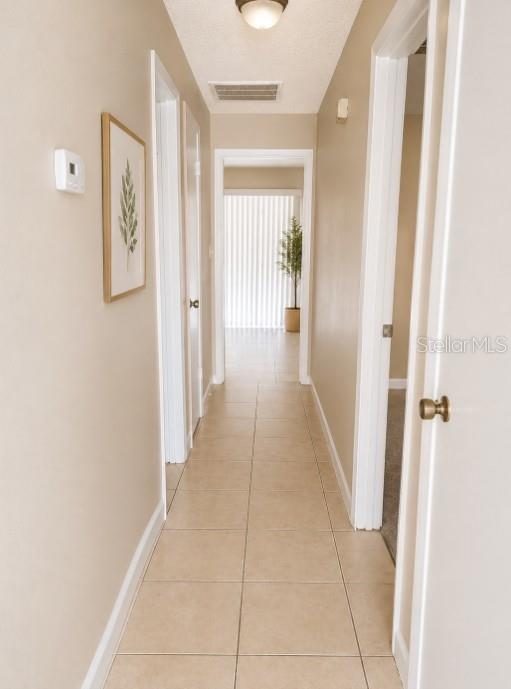 A hallway with beige tile flooring leads toward a doorway with vertical blinds — 1152 OLD SOUTH DRIVE, LAKELAND, FL