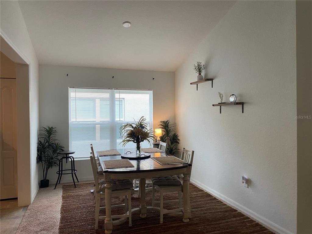 A dining room features a wooden table with chairs, a rug, and wall-mounted shelves — 1880 THOMPSON PRESERVE BOULEVARD, BARTOW, FL