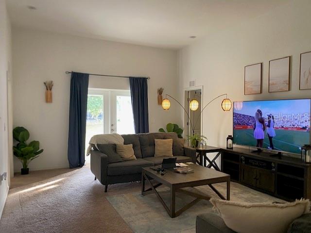 A living room features a gray sofa, a coffee table, and a large television — 1880 THOMPSON PRESERVE BOULEVARD, BARTOW, FL