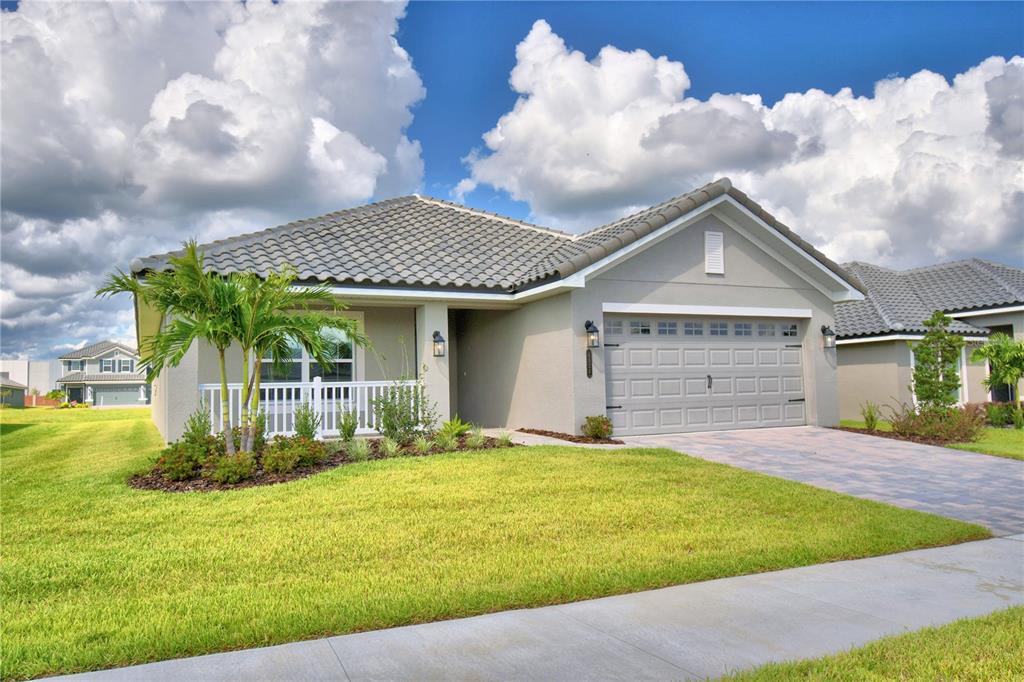 A light green single-story house with a two-car garage and a paved driveway — 4473 JULIANA LAKE DRIVE, AUBURNDALE, FL