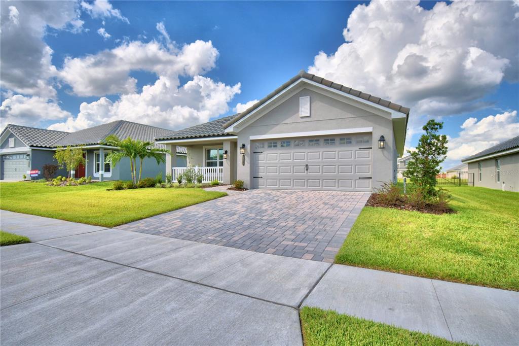 A single-story house with a light green exterior, a tiled roof, and a two-car garage — 4473 JULIANA LAKE DRIVE, AUBURNDALE, FL