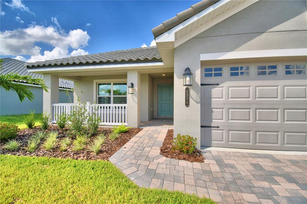 A light green house exterior features a covered porch, a front door, and a garage — 4473 JULIANA LAKE DRIVE, AUBURNDALE, FL