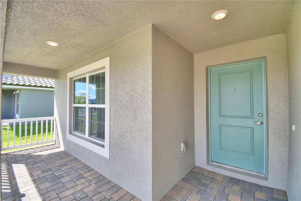 An open-concept living area features gray wood-look tile flooring, white walls, and a kitchen — 4473 JULIANA LAKE DRIVE, AUBURNDALE, FL