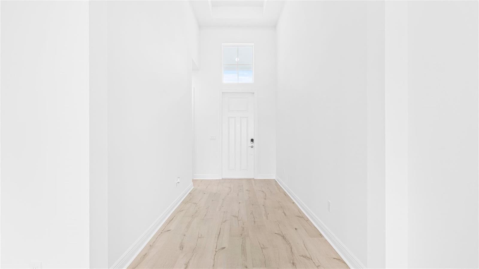 A bright, empty entryway features white walls, light wood-look flooring, and a tall front door — 5237 Rivo Alto Circle, Westlake FL 33470, WESTLAKE, FL