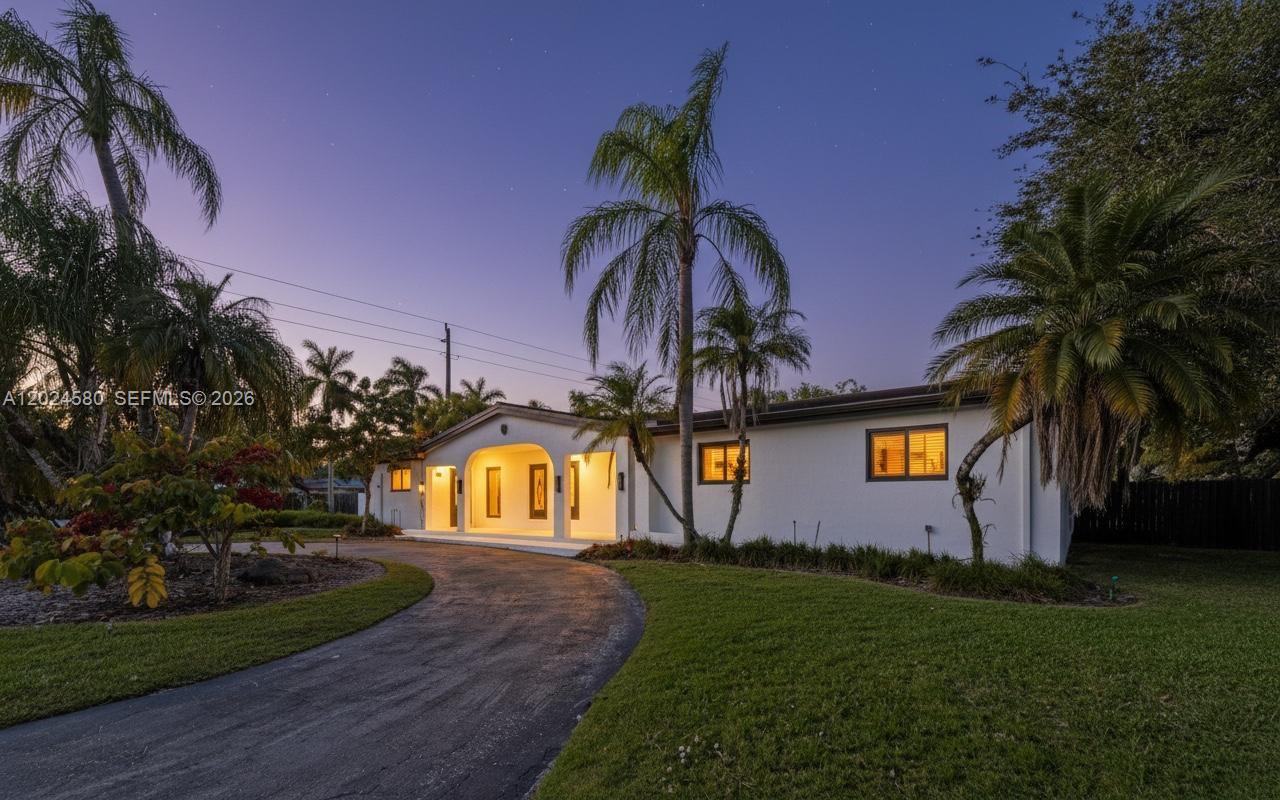 A white single-story house with a curved driveway and palm trees under a blue sky — 8695 SW 110th St, Miami FL 33156, MIAMI, FL
