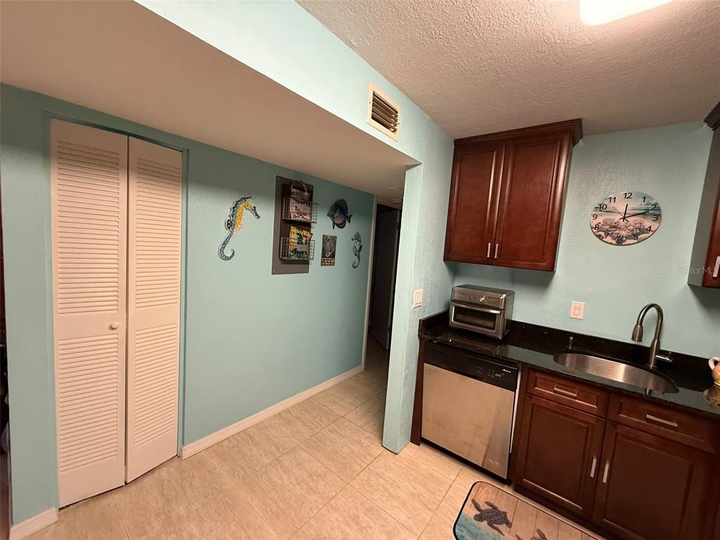A kitchen features light blue walls, dark wood cabinets, a stainless dishwasher, and a wall clock — 21280 BRINSON AVENUE UNIT 120, PORT CHARLOTTE, FL