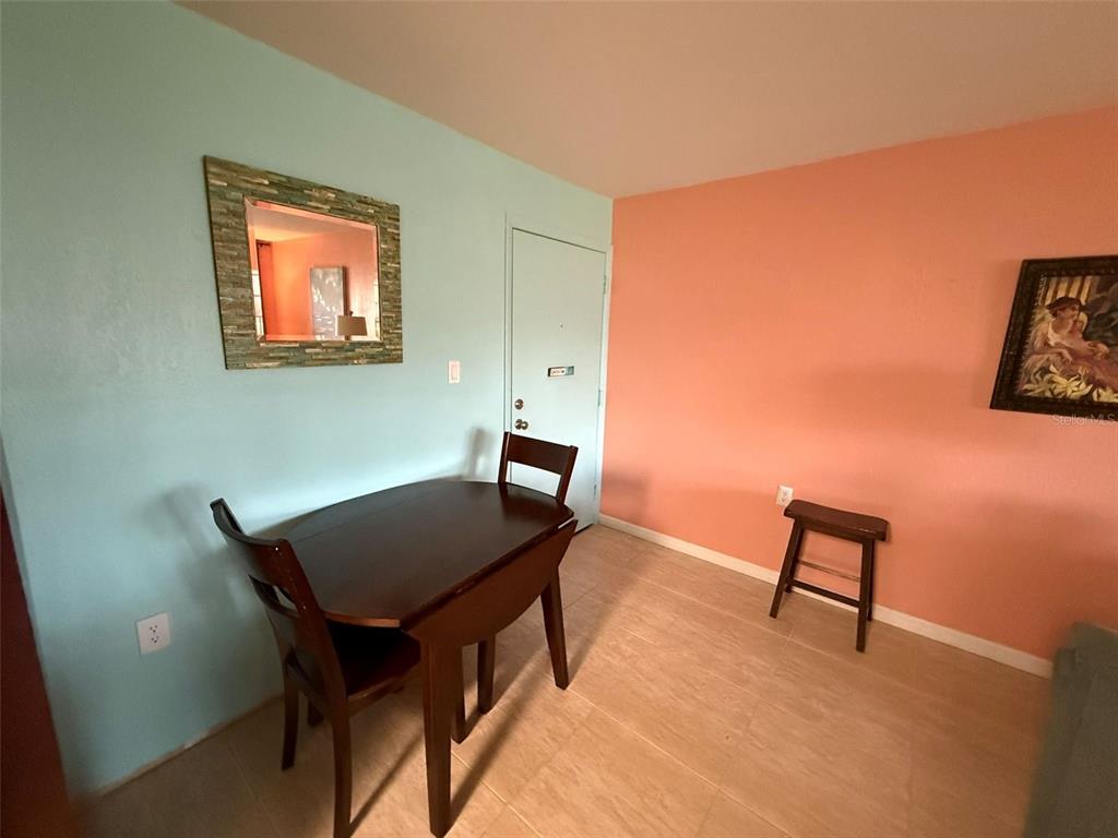 A dining area features a dark wood table, two chairs, a mirror, and a stool — 21280 BRINSON AVENUE UNIT 120, PORT CHARLOTTE, FL
