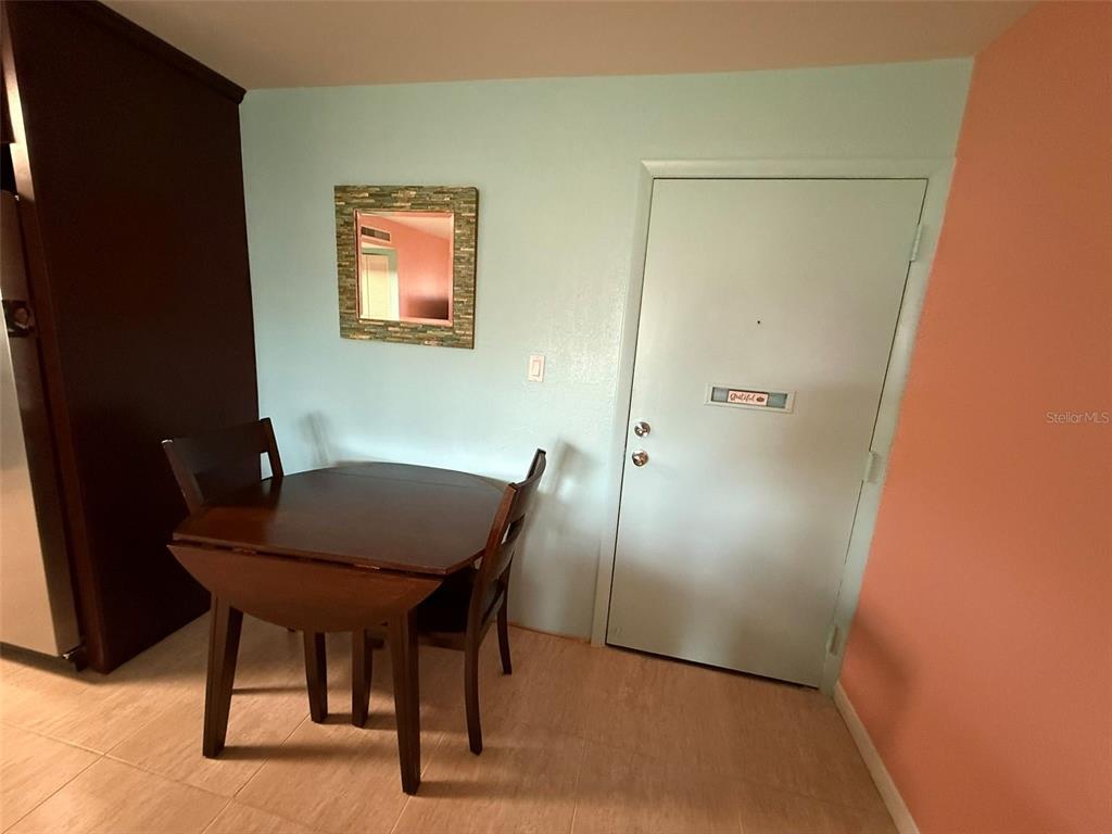 A small dining area features a wooden table, two chairs, a wall mirror, and a door — 21280 BRINSON AVENUE UNIT 120, PORT CHARLOTTE, FL