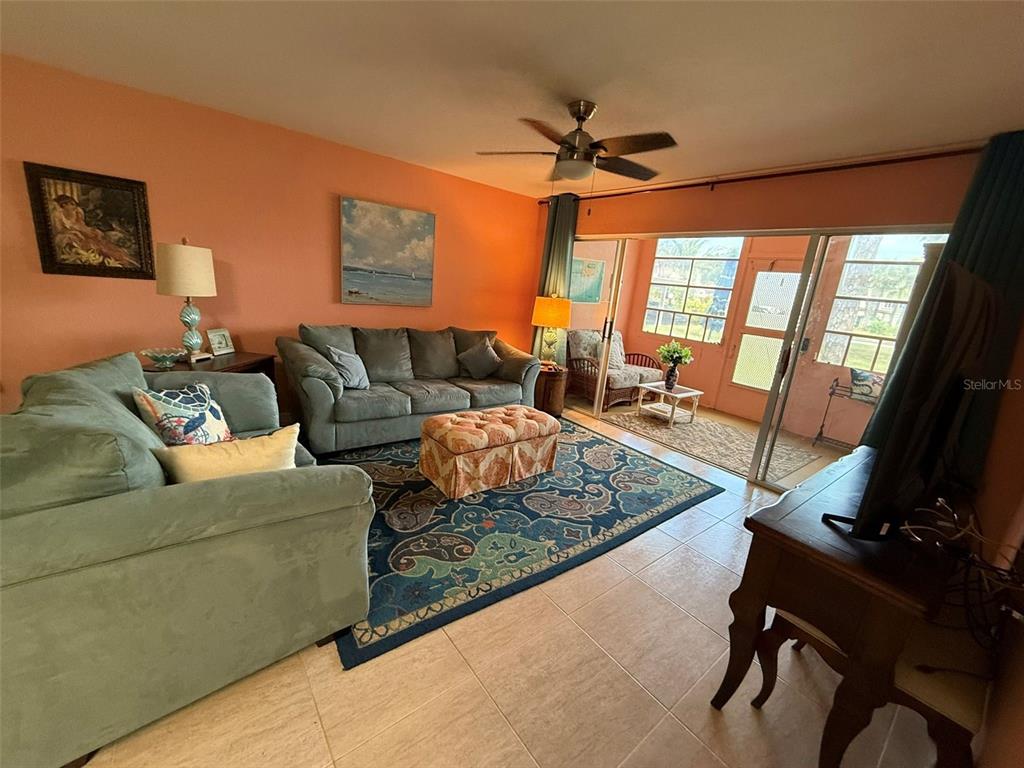 A living room with tile floors, a patterned area rug, and a sliding glass door — 21280 BRINSON AVENUE UNIT 120, PORT CHARLOTTE, FL