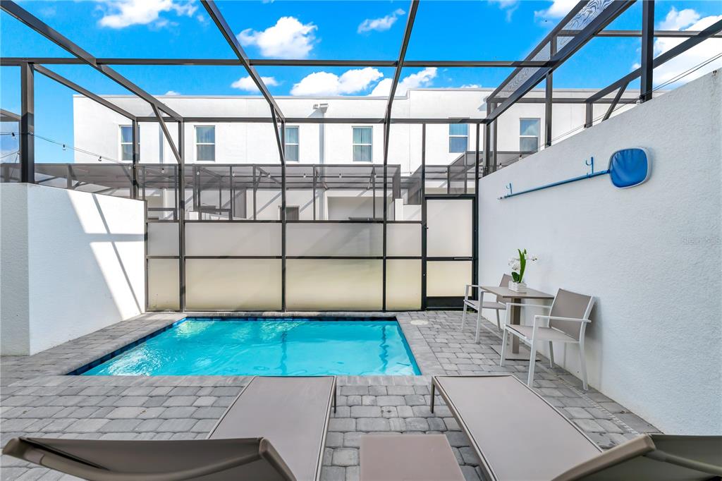 A small swimming pool sits on a paved patio enclosed by a screened-in lanai — 513 FAMAGUSTA DRIVE, DAVENPORT, FL