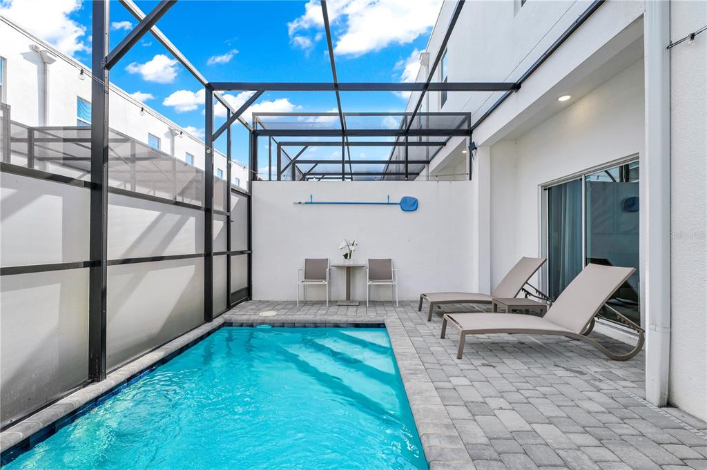 A small rectangular swimming pool sits on a paved patio enclosed by a screened lanai — 513 FAMAGUSTA DRIVE, DAVENPORT, FL