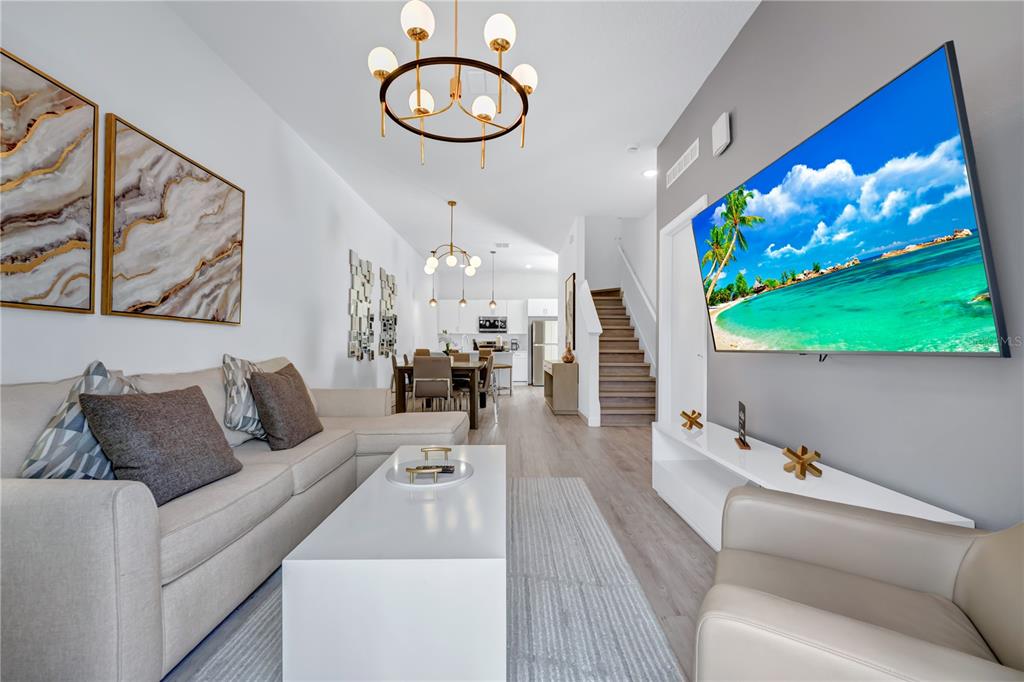 A modern living room features a beige sofa, white coffee table, and wall-mounted television — 513 FAMAGUSTA DRIVE, DAVENPORT, FL
