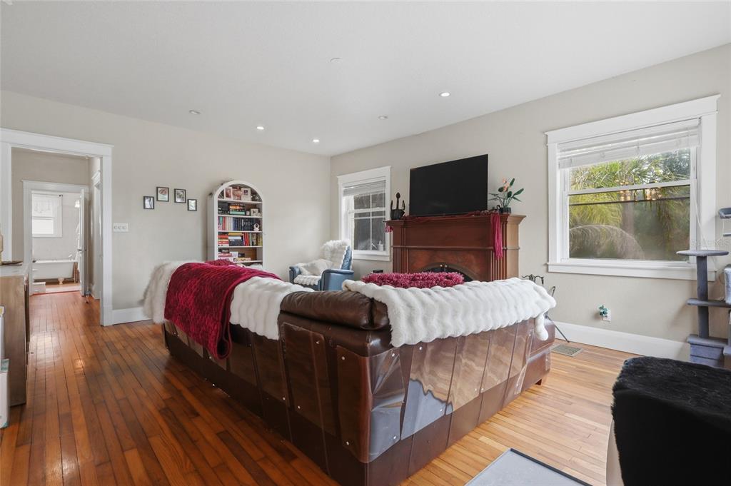A living room features a brown leather sofa, a fireplace with a television, and hardwood floors — 8115 N 37TH STREET, TAMPA, FL
