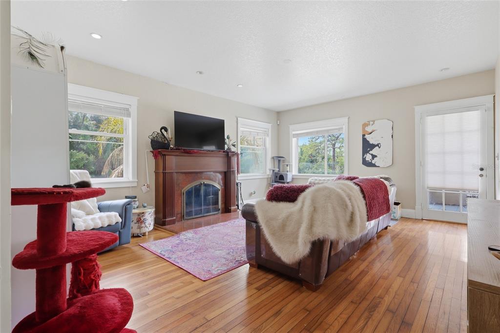 A living room features hardwood floors, a fireplace with a television, and a red cat tree — 8115 N 37TH STREET, TAMPA, FL