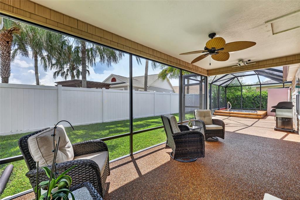 A screened-in patio features wicker furniture, a ceiling fan, and a view of the backyard — 1613 PENNECAMP DRIVE, THE VILLAGES, FL