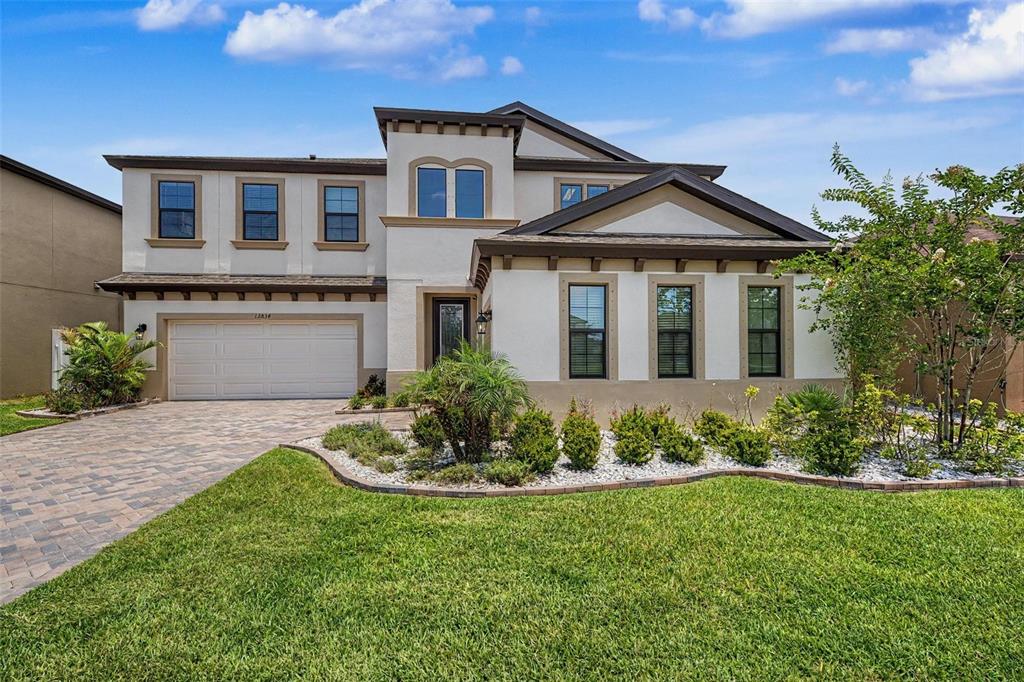 A two-story house with a white stucco facade, a two-car garage, and a landscaped yard — 12834 BOGGY CREEK DRIVE, RIVERVIEW, FL