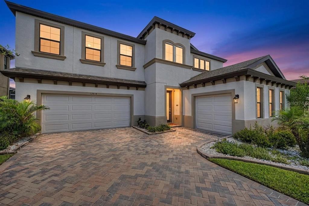 A two-story house with a three-car garage and a paved driveway at dusk — 12834 BOGGY CREEK DRIVE, RIVERVIEW, FL