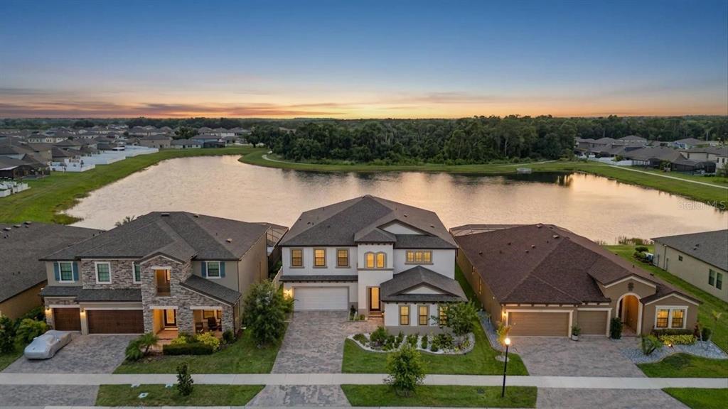 An aerial view shows three suburban houses situated along the edge of a large lake — 12834 BOGGY CREEK DRIVE, RIVERVIEW, FL