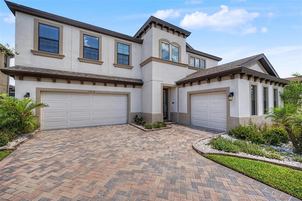 A two-story stucco house features a three-car garage and a paved driveway — 12834 BOGGY CREEK DRIVE, RIVERVIEW, FL