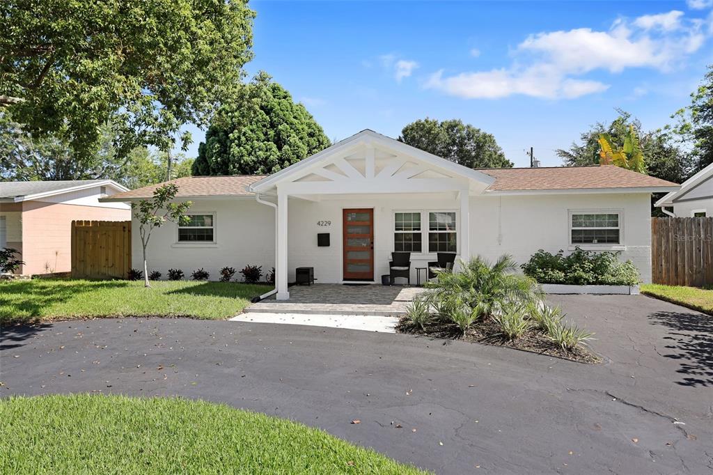 A white single-story house features a covered front porch, a brown door, and a driveway — 4229 7TH AVENUE N, ST PETERSBURG, FL
