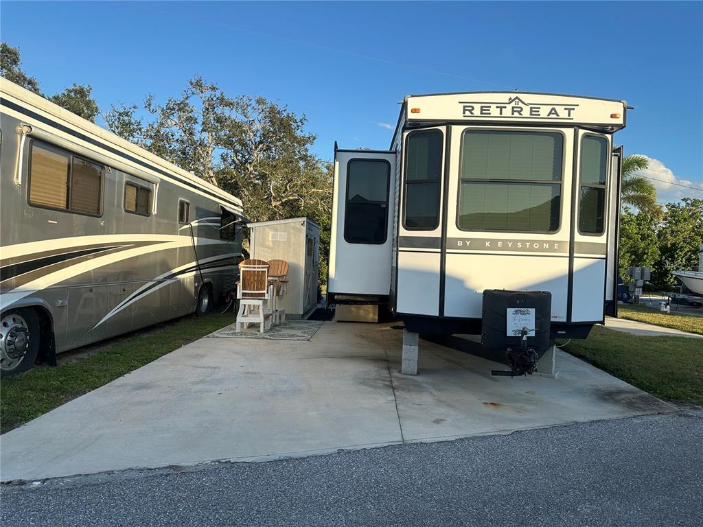 A Keystone Retreat travel trailer is parked on a concrete pad next to another RV — 136 BAHIA DRIVE, PALMETTO, FL