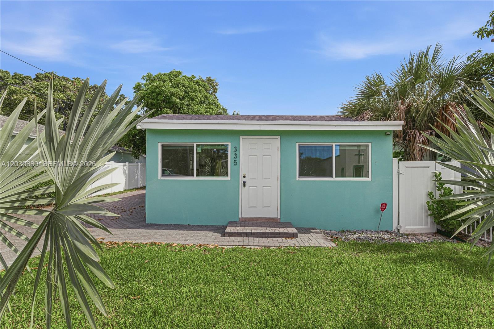 A small, light green, single-story house features a white front door and two windows — 335 NE 12th Ave, Boynton Beach FL 33435, BOYNTON BEACH, FL