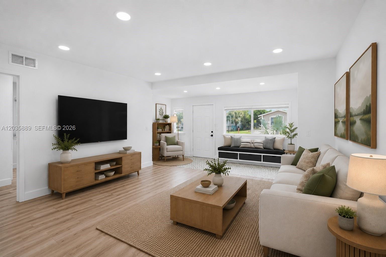 This living room features light wood flooring, a wall-mounted television, and a neutral sofa — 335 NE 12th Ave, Boynton Beach FL 33435, BOYNTON BEACH, FL